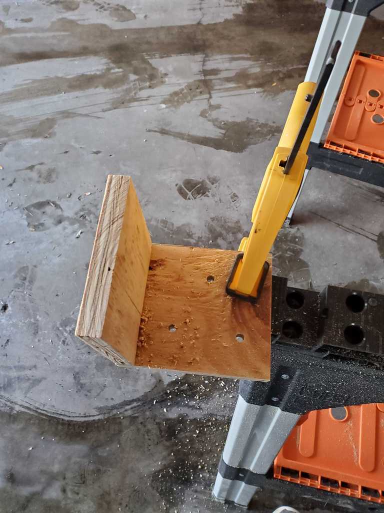 A L shaped wooden bracket with 3 holes drilled into a face